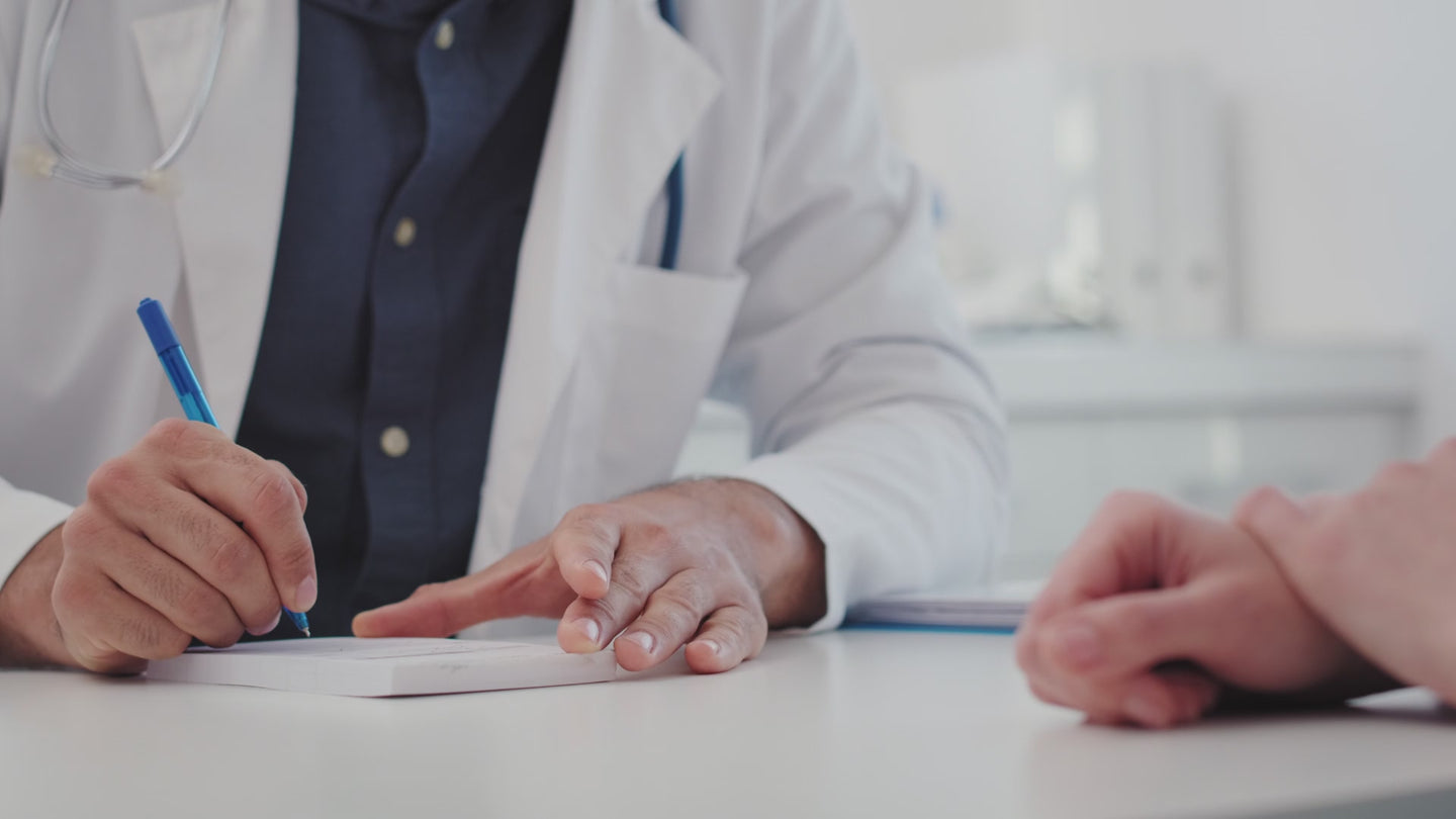 Clinician writing at a consultation desk